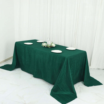 Green tablecloth draped over a table set for dining with white plates.