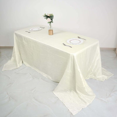 Elegant cream tablecloth draped over a dining table with plates and utensils.