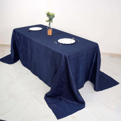 Navy blue tablecloth draped elegantly over a dining table with plates and vase.
