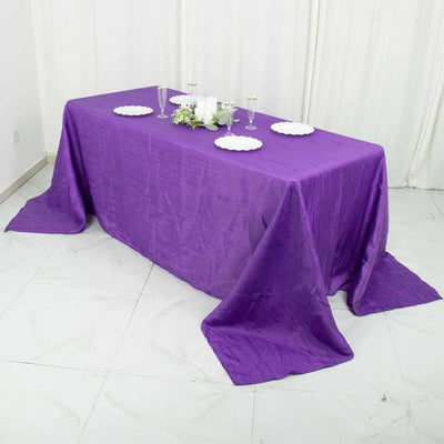 Purple tablecloth draped elegantly on a table with decorative plates and candles.