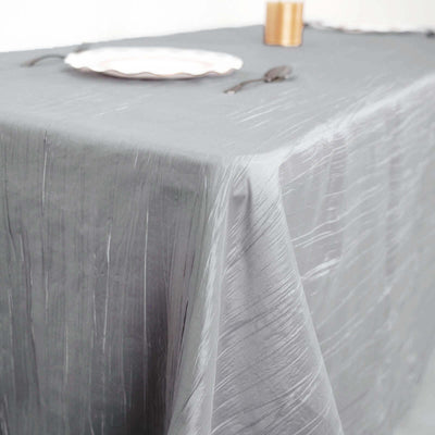 Gray textured tablecloth draping over a table with a plate and utensils.