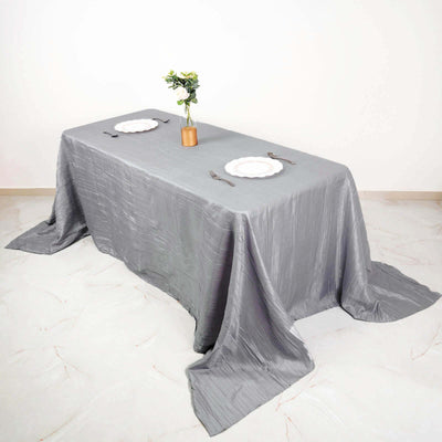 Grey tablecloth draped over a dining table with plates and a vase of flowers.