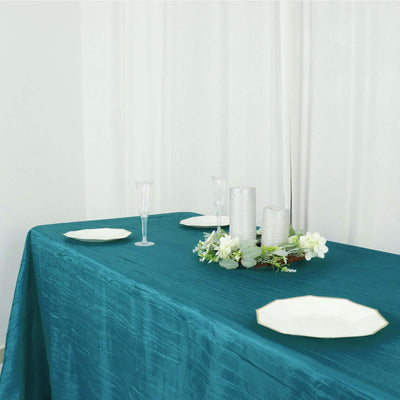 Elegant teal tablecloth draped over a table set with plates and decorative accents.