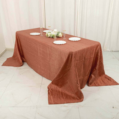 Copper tablecloth draped over a table with plates and floral arrangement.