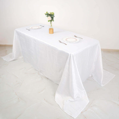Elegant white table setting with a floral centerpiece and dinnerware.