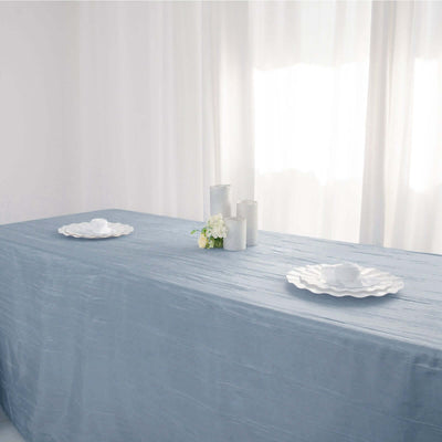 Elegant blue tablecloth draped over a table with white dinnerware and candles.