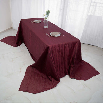 Elegant burgundy tablecloth draping over a dining table with plates and cutlery.