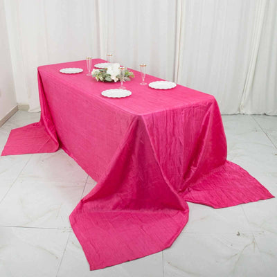Pink tablecloth draped over a table with decorative plates and candles.
