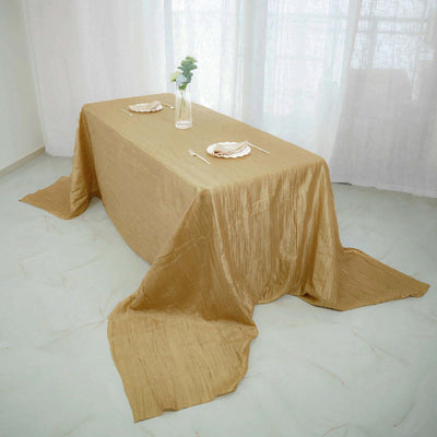 Elegant gold tablecloth draped over a dining table with simple decor.