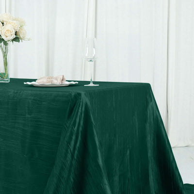 Elegant dark green tablecloth on a table with decor and glassware.