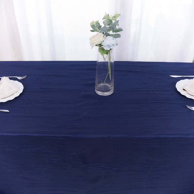 Navy blue tablecloth with white plates and a vase of flowers on a dining table.