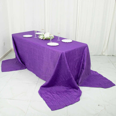 Purple tablecloth draped elegantly over a table with decorative plates and centerpieces.