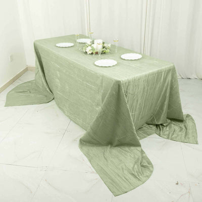 Green tablecloth draped elegantly over a table with white plates and decor.