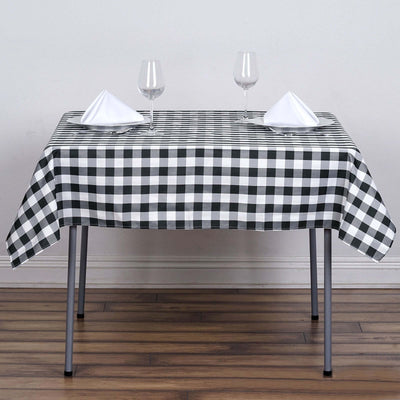 Black and white checkered tablecloth on a dining table with glasses and napkins.