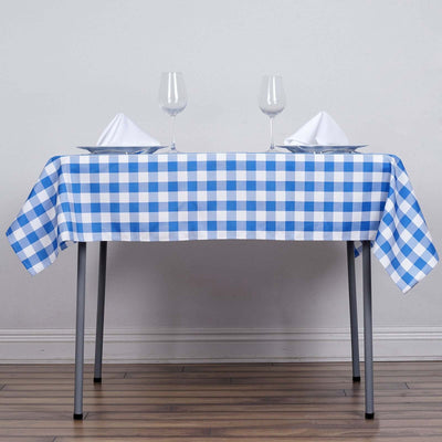 Blue and white checkered tablecloth on a dining table with glasses and napkins.