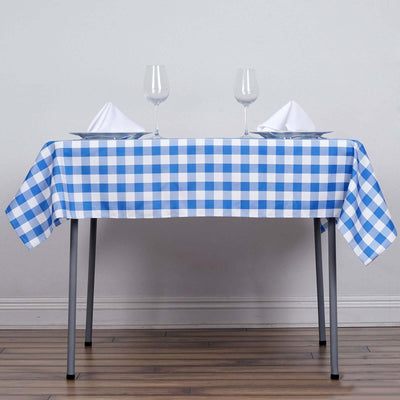 Blue and white checkered tablecloth on a dining table with glassware and napkins.