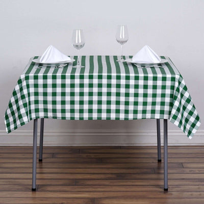 Green and white checkered tablecloth on a dining table with glasses and napkins.