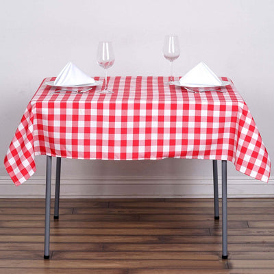 Red and white checkered tablecloth on a dining table with wine glasses and napkins.