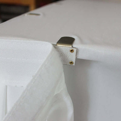 Metal clip securing fabric to a white surface