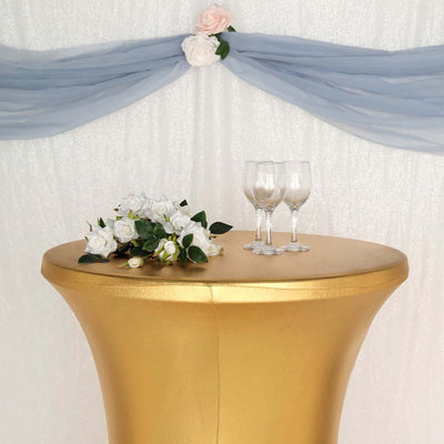 Gold cocktail table with floral arrangement and glasses, decorated backdrop.