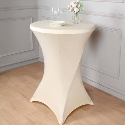 Cream-colored stretch table cover on a round table with glassware and flowers.