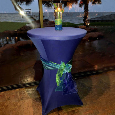 Navy cocktail table with a green and blue ribbon and a colorful drink on top.