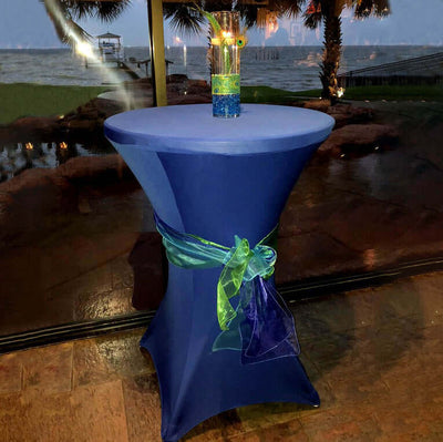 Navy table cloth with a colorful ribbon and drink on a table by the water.
