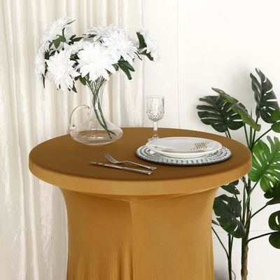 Elegant table setting with golden tablecloth, plates, and floral centerpiece.