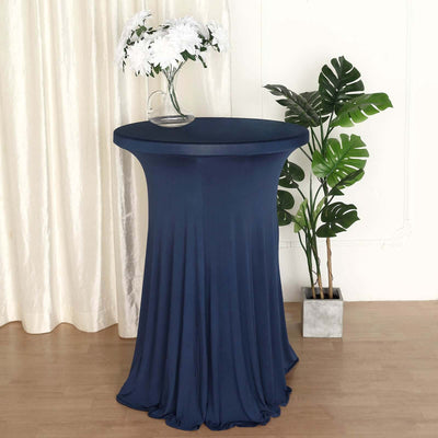 Navy stretch table cover on a round table with flowers and plants in the background.