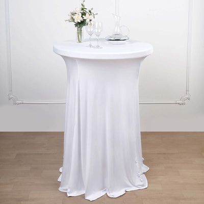 White cocktail table with a fitted cover, glassware, and a vase of flowers.