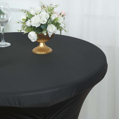 Elegant black tablecloth with a gold vase and white flower arrangement.