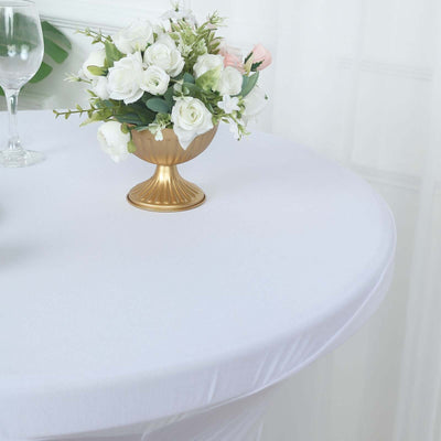 Gold vase with white and pink flowers on a white tablecloth.
