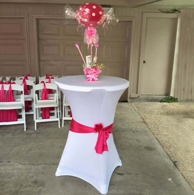 Pink and white candy-themed party table with a decorative centerpiece.