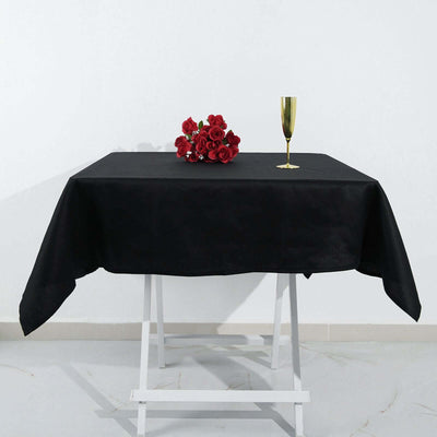 Black tablecloth with red roses and a gold glass on a white backdrop.