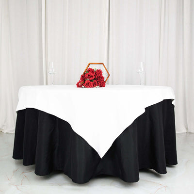 Elegant table setting with white and black tablecloth, roses, and glassware.