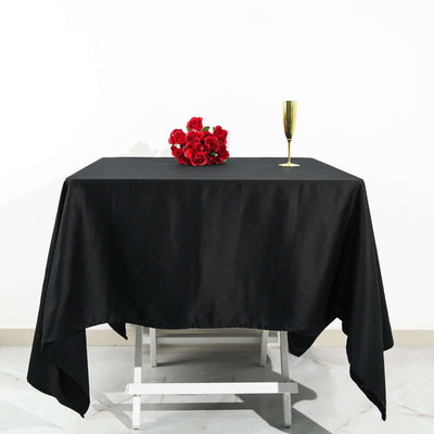 Black tablecloth on a table with red roses and a champagne flute.