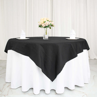 Black tablecloth draped over a round table with a floral centerpiece.