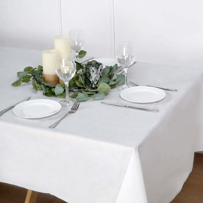 Elegant dining table set with candles, glasses, and greenery centerpiece.