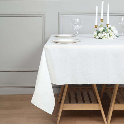 Elegant white tablecloth draped over a wooden table with candles and floral centerpiece.