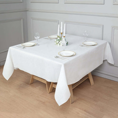 Elegant white tablecloth set for dining with plates and decorative centerpiece.
