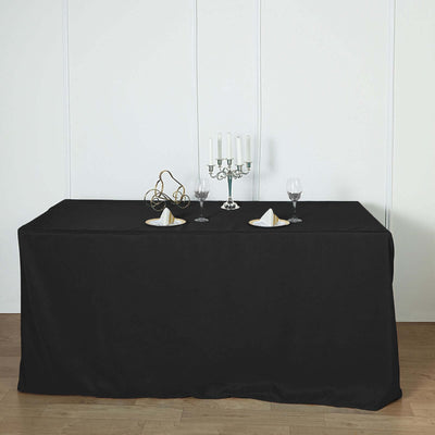 Elegant black tablecloth set with candles and glassware.