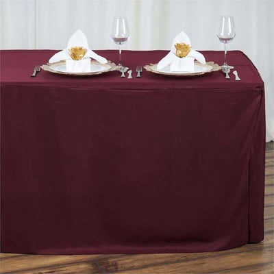 Burgundy tablecloth with elegant place settings and napkin folds