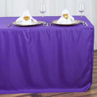 Purple tablecloth with elegant table setting and napkin folds.