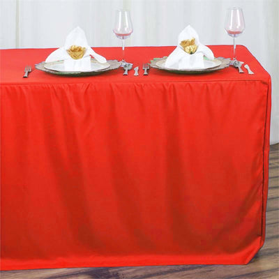 Red tablecloth elegantly draped on a table set for dinner with plates and glasses.