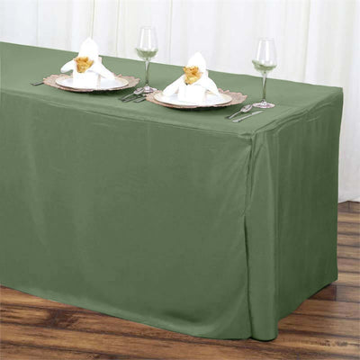 Olive green tablecloth on a dining table set for two with elegant napkin folds.
