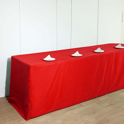 Red tablecloth draped over a long table with white plates on top.