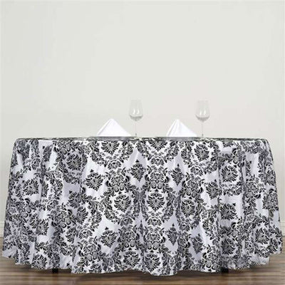 Elegant black and white damask tablecloth draped over a round table.