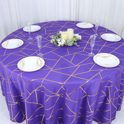 Purple geometric tablecloth on round table with white plates and decor.
