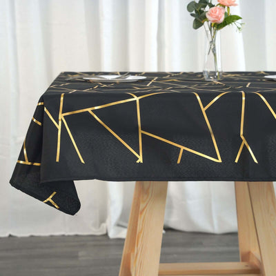 Black tablecloth with gold geometric pattern, elegantly styled with a vase and flower.