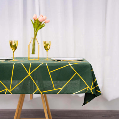 Green geometric tablecloth with gold accents, styled with tulips and glassware.